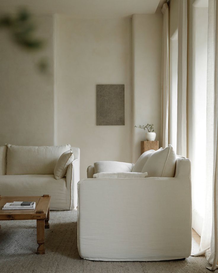 a living room with white furniture and curtains