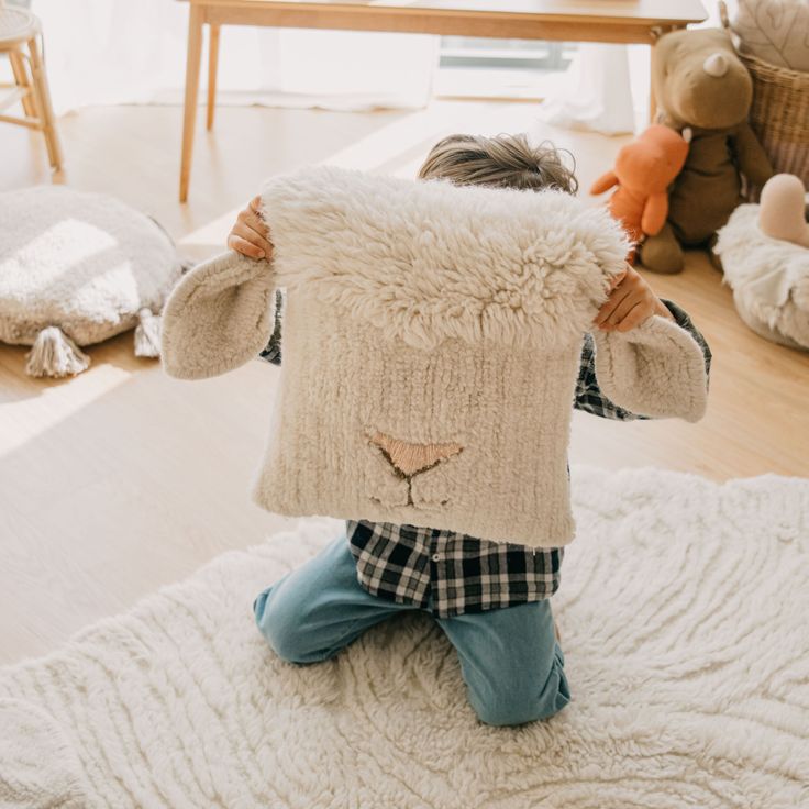 a little boy sitting on top of a bed holding a stuffed animal over his head