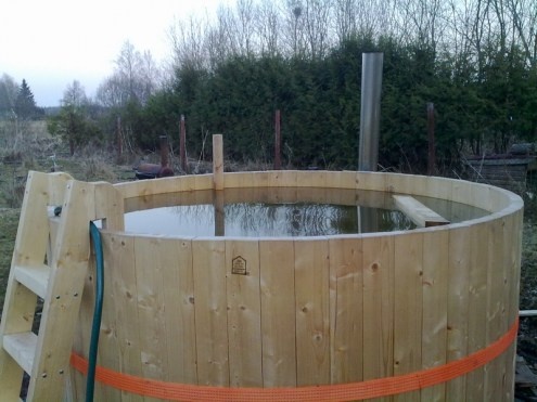 a large wooden hot tub sitting in the middle of a field