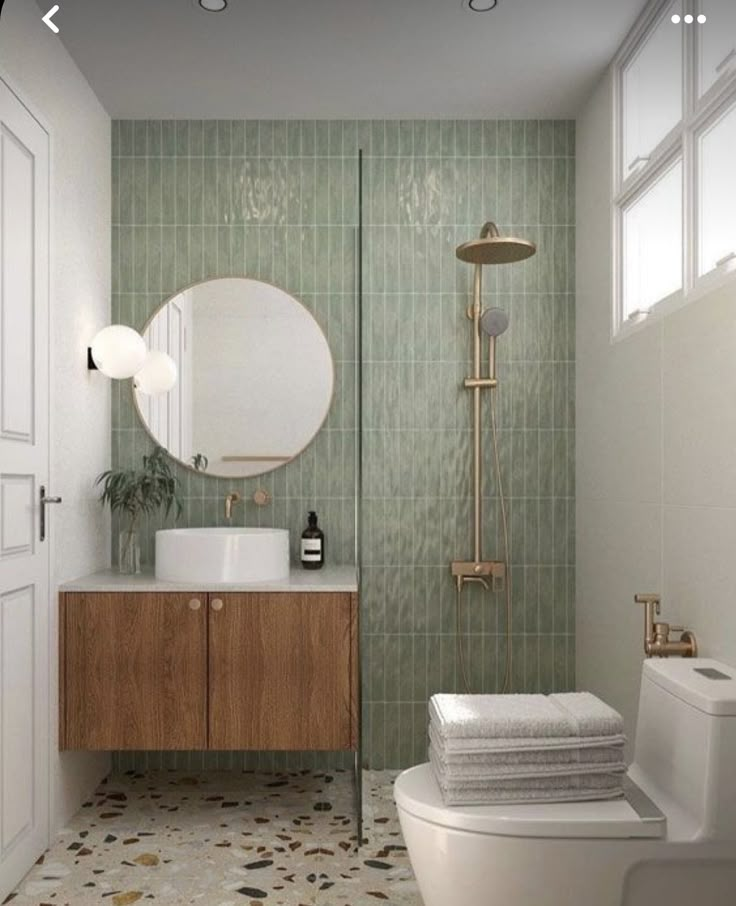 a bathroom with green tiled walls and flooring next to a sink, toilet and shower