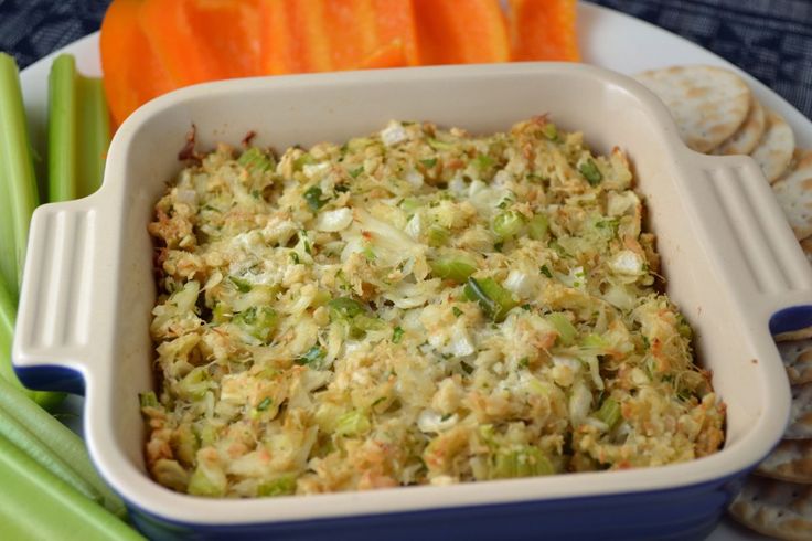 a casserole dish with carrots, celery and crackers on the side