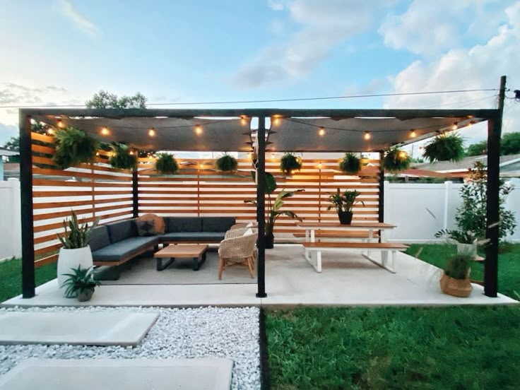 an outdoor living area with couches, tables and potted plants