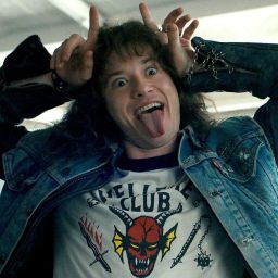 a young man with his tongue out making a silly face while wearing a jean jacket