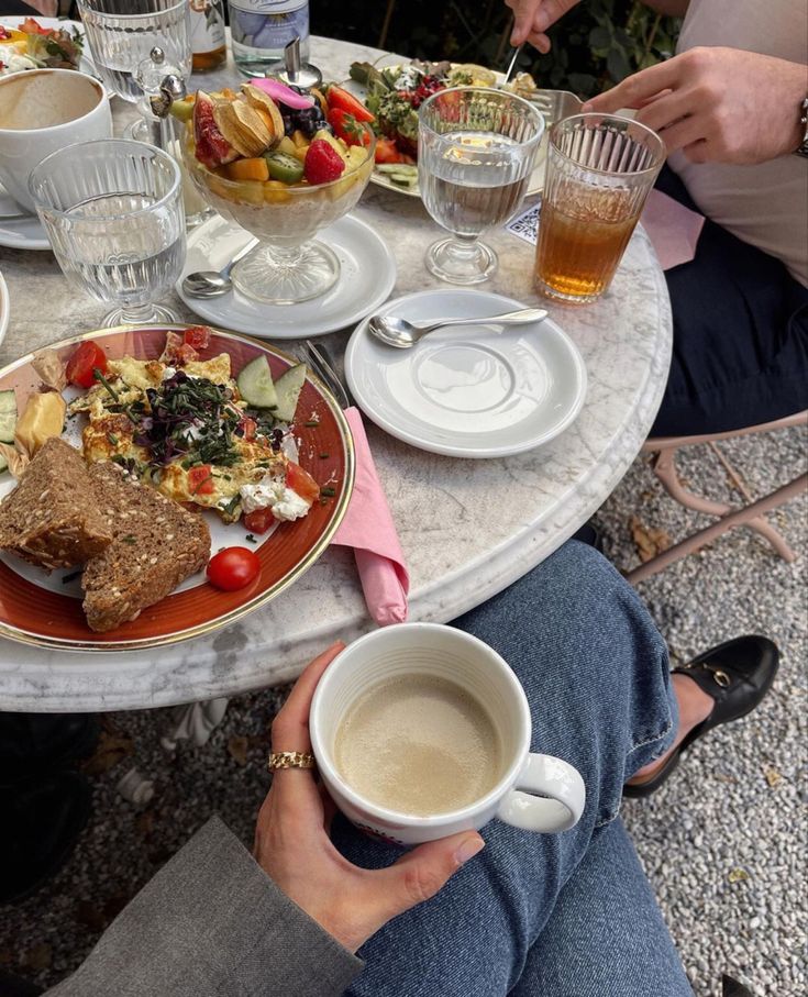 a person sitting at a table with food and drinks in front of them on their plates