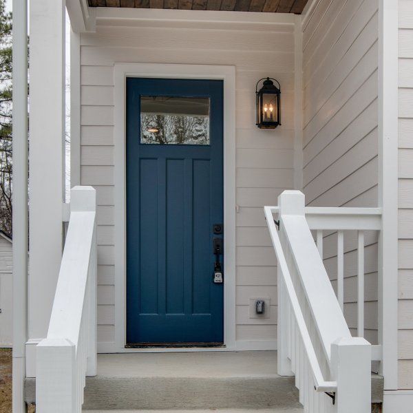 a blue front door on a white house with steps leading up to it and a light hanging above the door