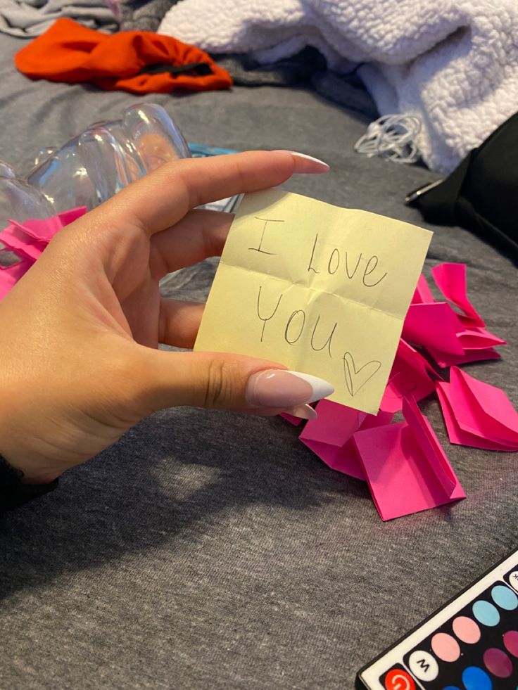 a person holding a piece of paper with the words i love you written on it