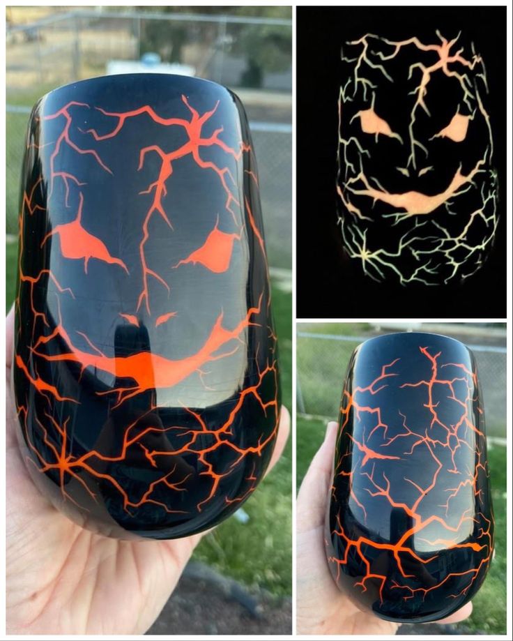 a hand holding up a black and orange glass with lightning on it