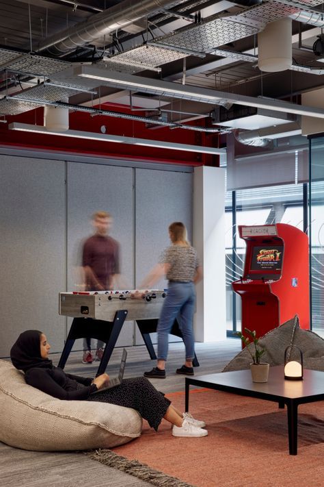 two people are playing video games in an office setting with bean bag chairs and tables