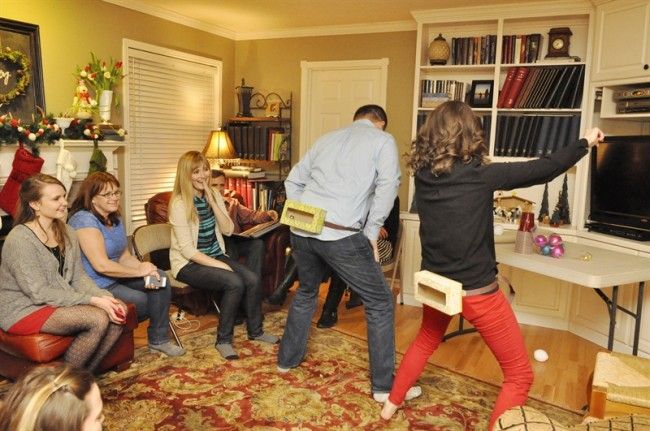 a group of people sitting around in a living room playing video games on the nintendo wii