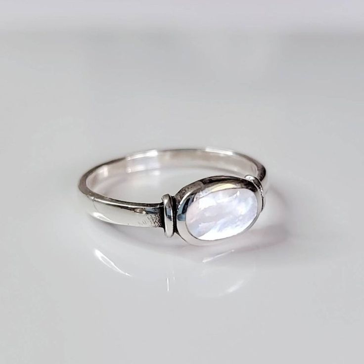 a close up of a ring on a white surface with a small stone in the middle