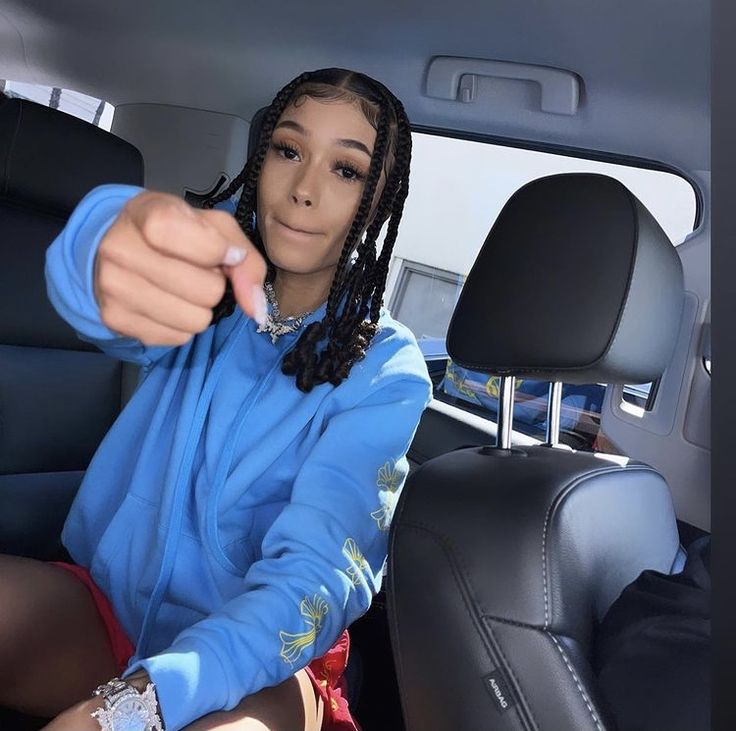 a young woman sitting in the back seat of a car pointing at something with her finger