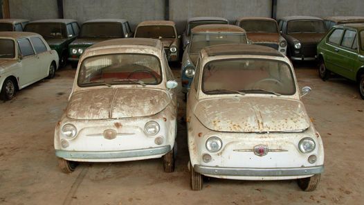 several old cars are parked in an abandoned garage with no one on the front and side