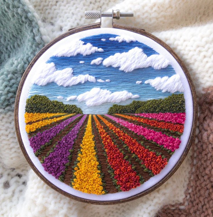 a hand embroidered picture of a colorful field