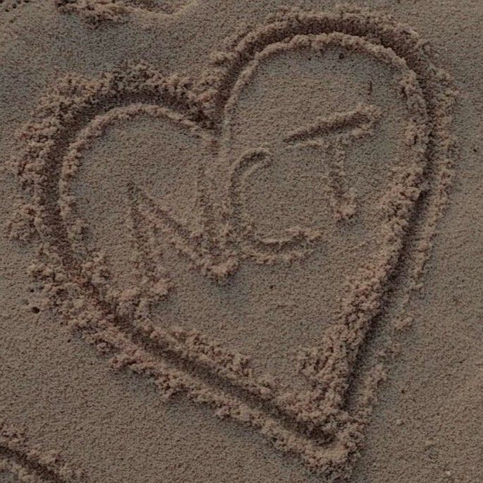 a heart drawn in the sand with an image of a woman's face on it