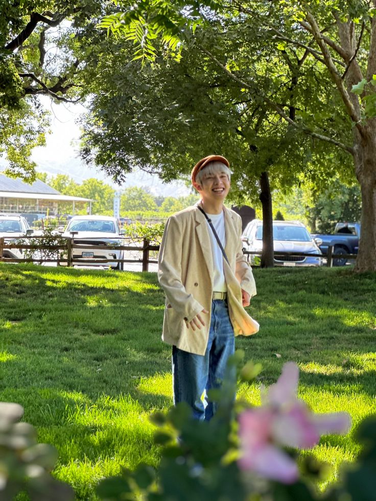 a man standing in the grass holding a frisbee and wearing a tan jacket