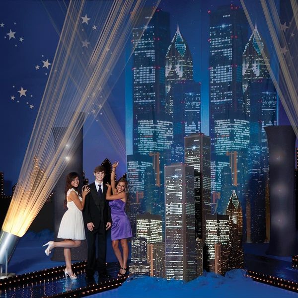 two women and a man standing in front of a cityscape at night time