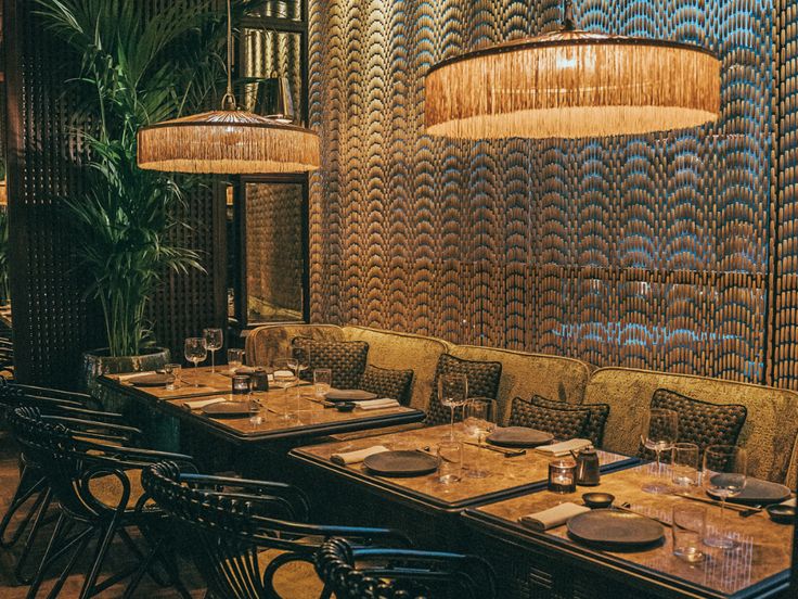 a long table with place settings in front of a wall made out of woven reeds