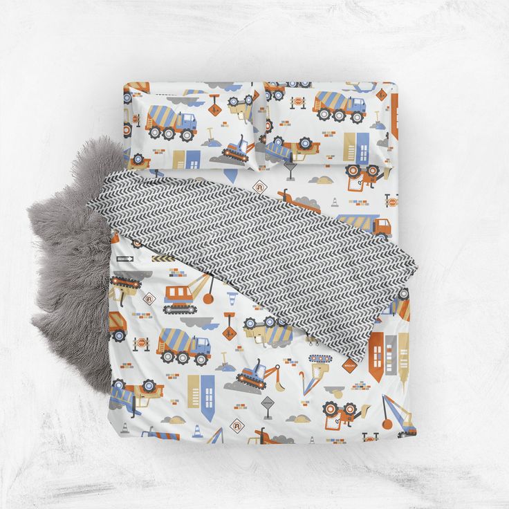 a baby blanket with construction trucks on it and a gray pom - pom