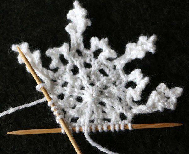 a crocheted snowflake with two knitting needles