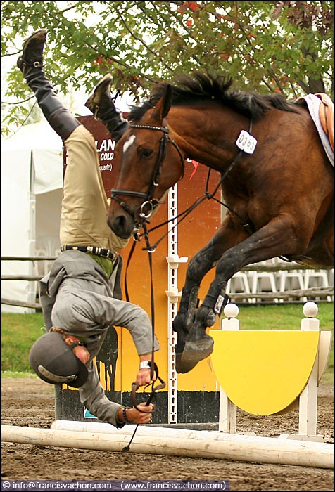 a man riding on the back of a brown horse next to a person jumping over an obstacle