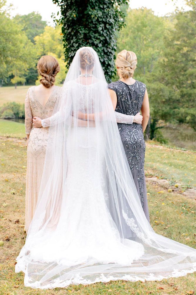 two women standing next to each other in front of a wedding veil on the grass