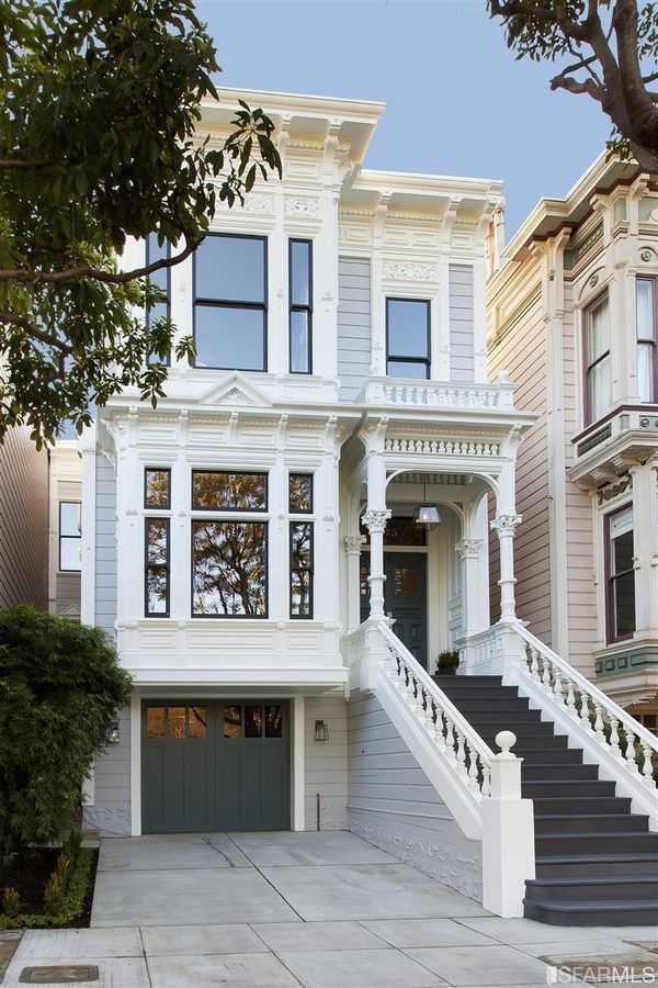 a large white house with stairs leading up to it's front door and windows