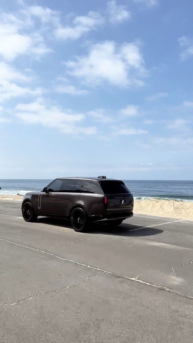 an suv is parked on the beach near the ocean