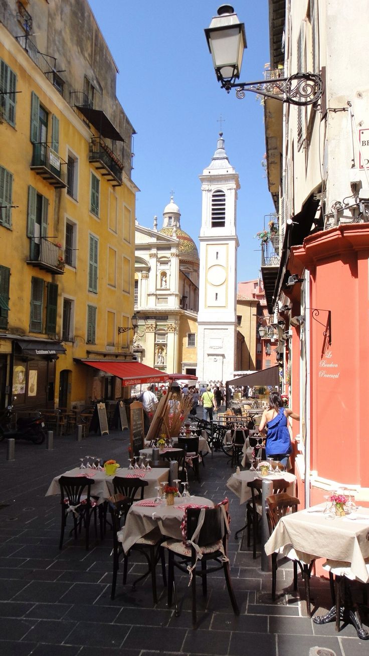 tables and chairs are set up in the middle of an alleyway with tall buildings