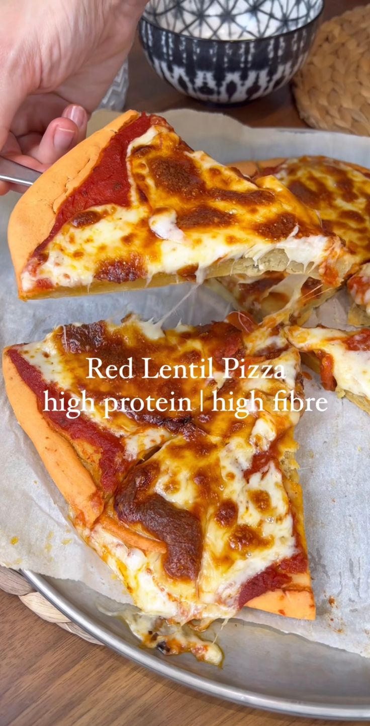 two slices of pizza sitting on top of a metal pan next to a bowl and spoon