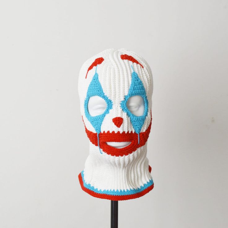 a knitted clown mask with red, white and blue paint on it's face