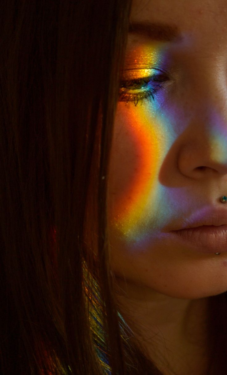 a woman with bright rainbow makeup looks at the camera