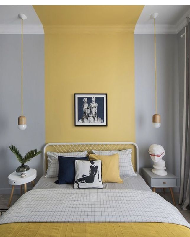 a bedroom with yellow walls and white bedding, artwork on the wall above the bed