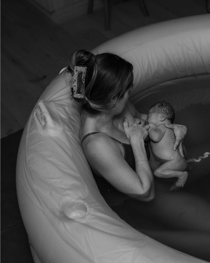 a woman sitting in an inflatable pool with a baby