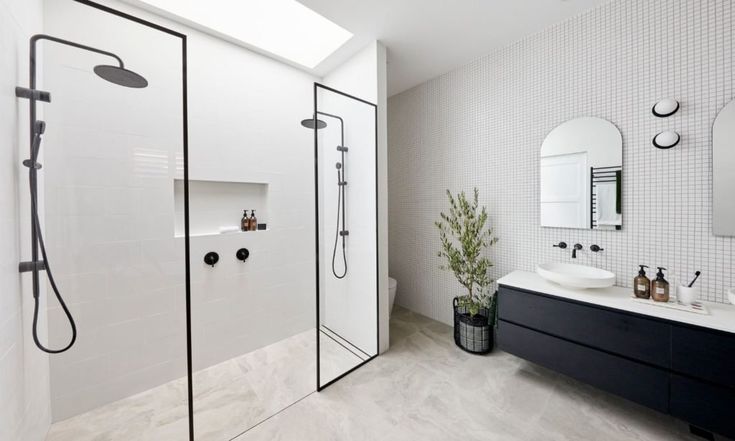 a white bathroom with two sinks and a walk in shower next to a large mirror