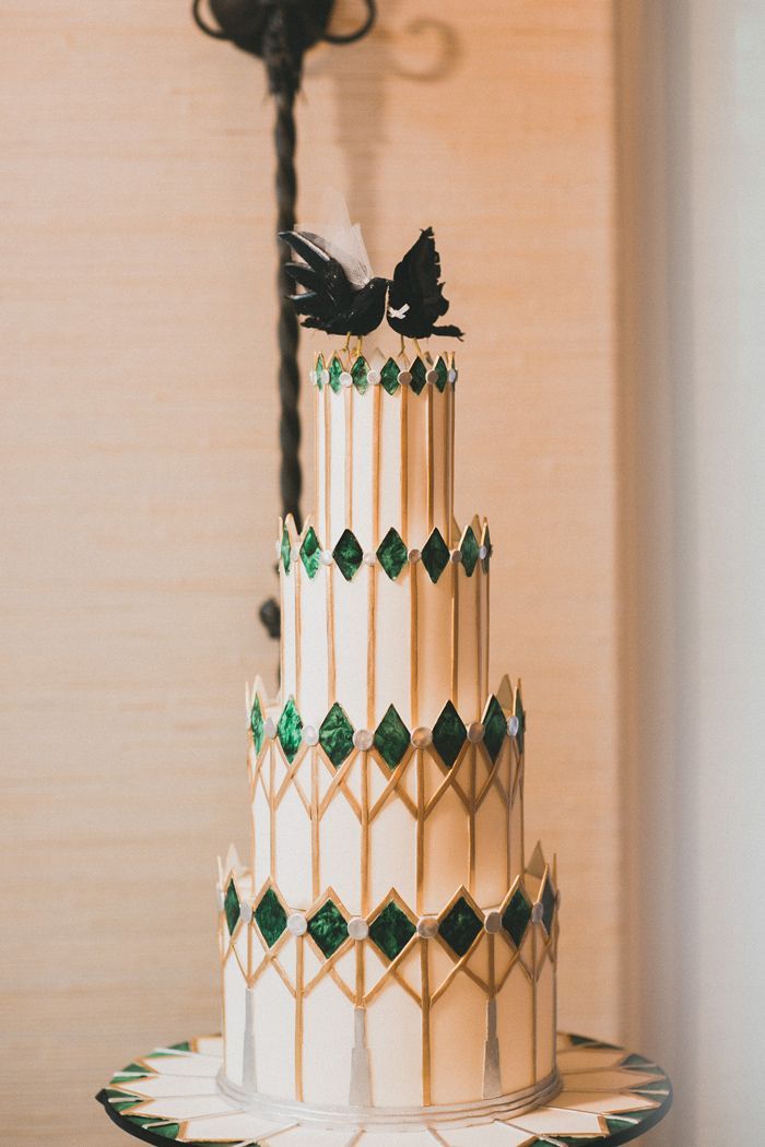 a three tiered white cake with green and black decorations on it's side