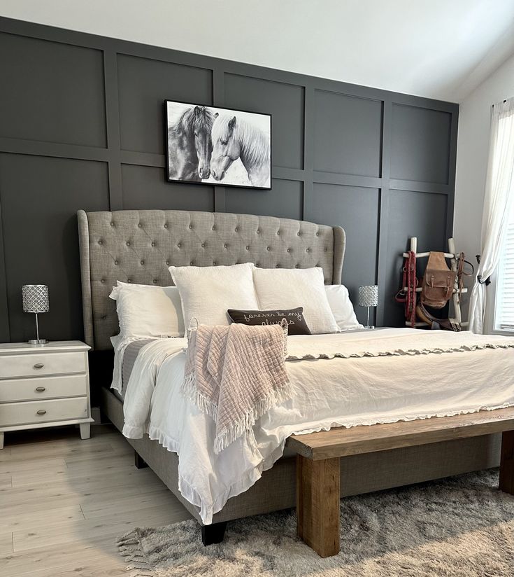 a large bed with white sheets and pillows in a bedroom next to a painting on the wall