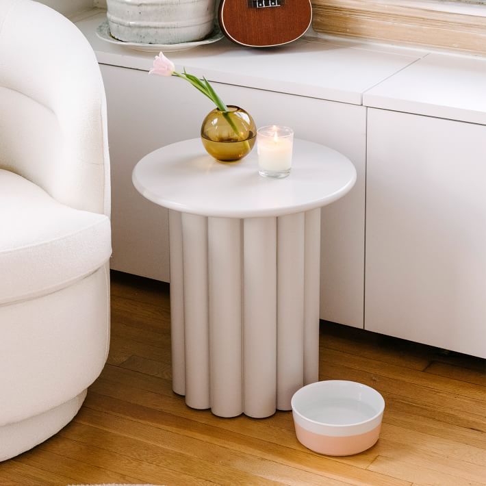 a small table with a vase on it next to a white chair