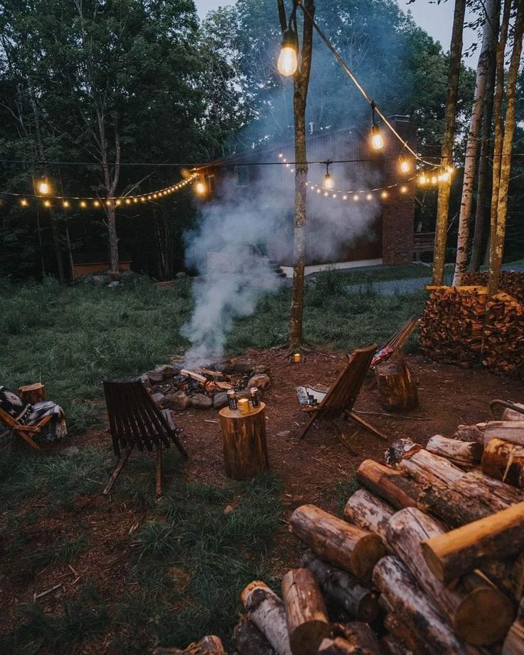 an outdoor fire pit surrounded by logs and string lights