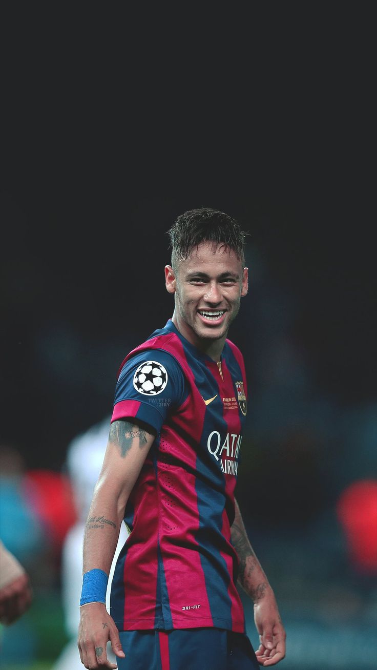 a man with tattoos on his arm standing in front of a soccer ball and smiling at the camera