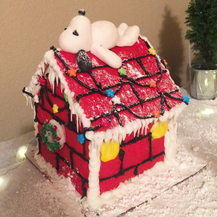 there is a cake that looks like a house with snow on the roof and lights around it