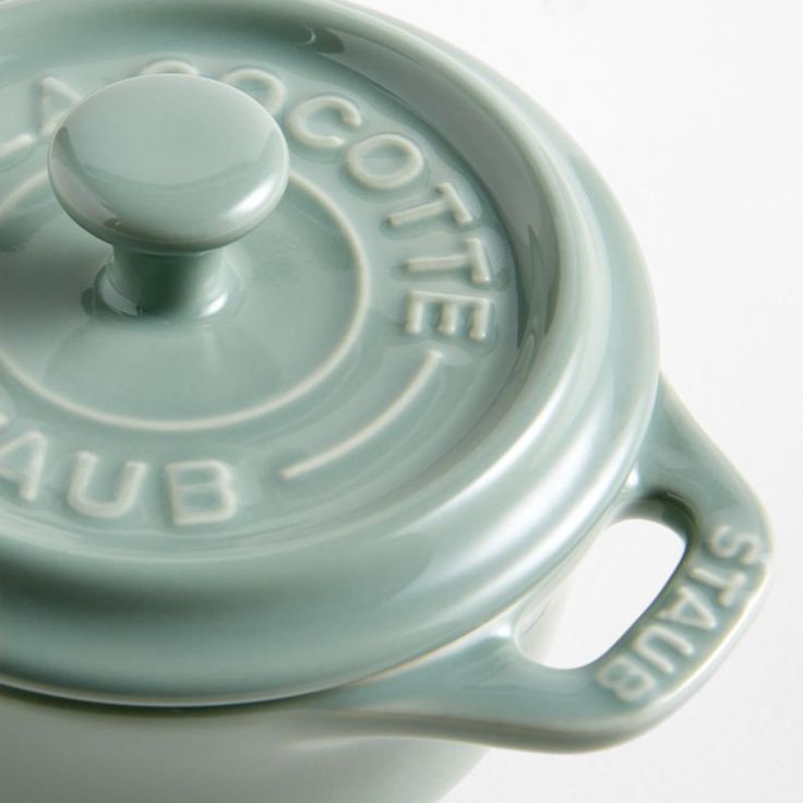 a close up of a ceramic pot on a white surface with the lid down and words written in cursive writing