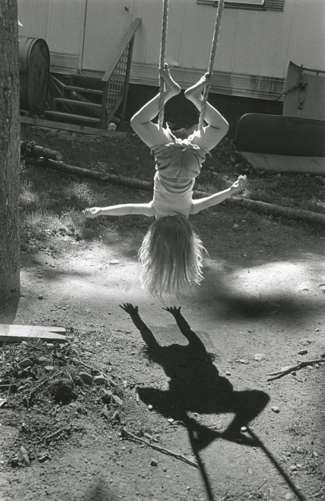 a girl is swinging on a rope in the air with her hands behind her head