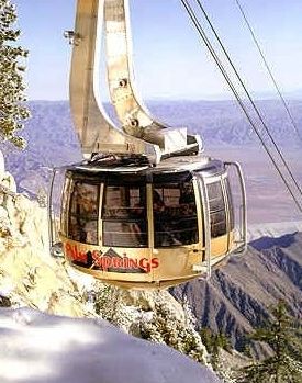 a ski lift going up the side of a mountain with snow on it's ground