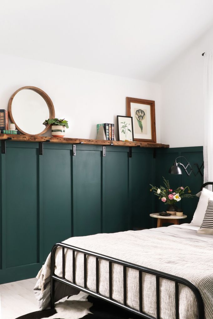 a bedroom with dark green painted walls and white bedding, along with bookshelves