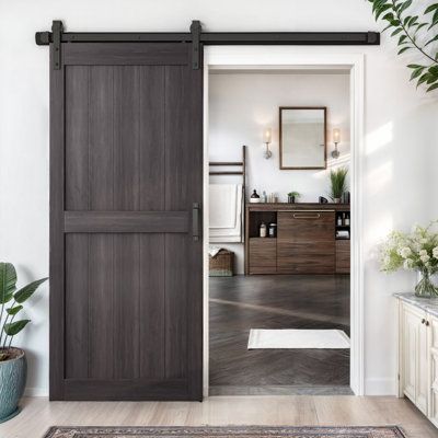 an open door leading to a bathroom with potted plants on the floor and a rug