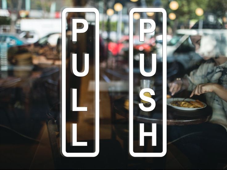 two people sitting at a table in front of a window with the word push on it