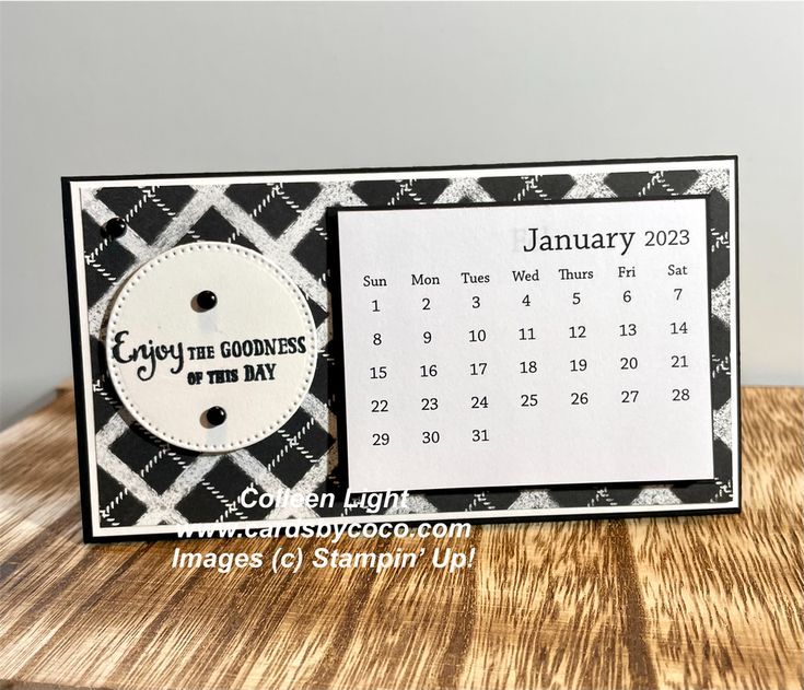 a card with a calendar on it sitting on top of a wooden table next to a clock