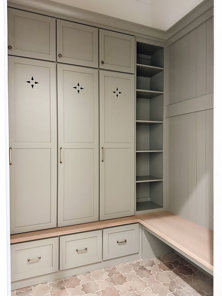 an empty walk - in closet with white cupboards and beige tile flooring is shown