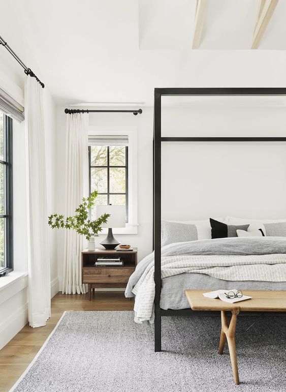 a bedroom with a four poster bed and white walls