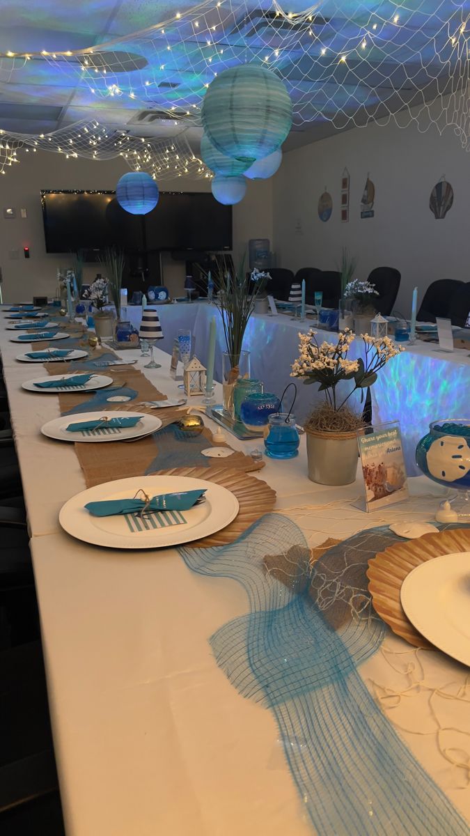 a table set up with plates and place settings for an ocean themed dinner or party